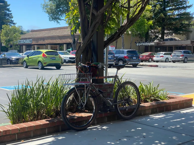 Bike with empty basket at an outdoor shopping center in Marin, locked to itself.