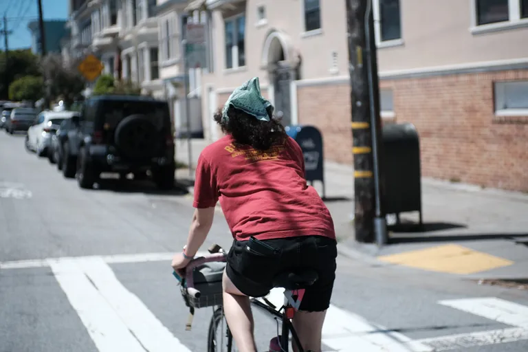 Natalie riding away from the camera on her black sparkly Crust Lightning Bolt with pink accents. She's wearing a red shirt, black shorts and a mint bandana