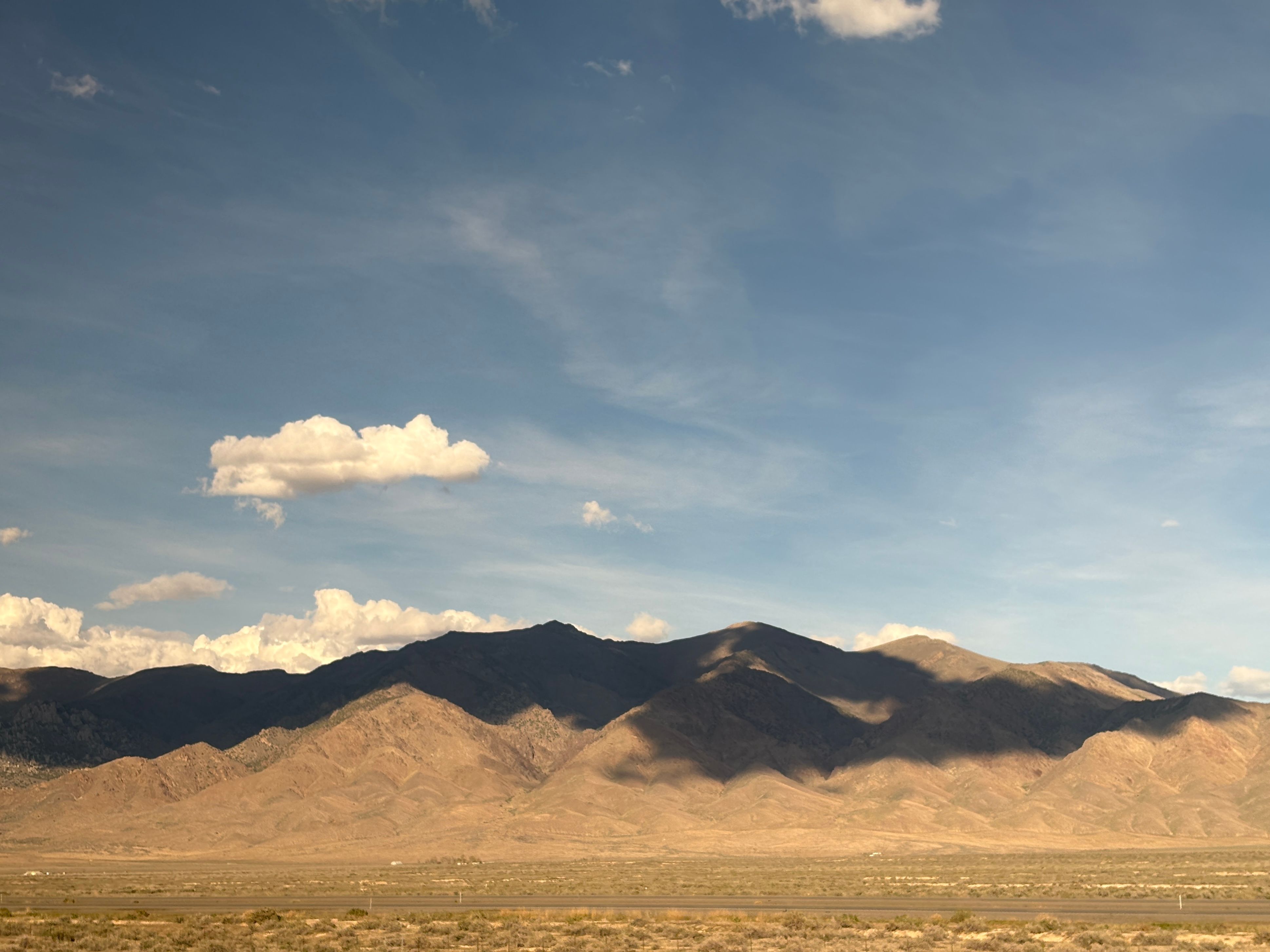 In the high desert, clouds cast huge, solid shadows over the mountains that soar up from the flat valley floor.